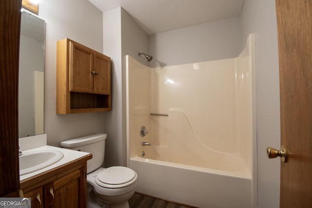 bathroom with toilet, washtub / shower combination, wood finished floors, and vanity