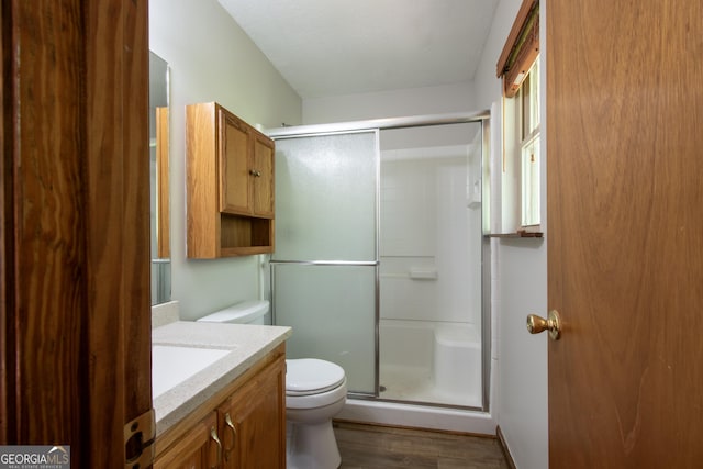 bathroom featuring vanity, an enclosed shower, wood finished floors, and toilet