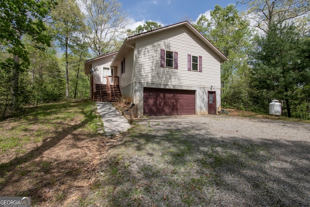 view of property exterior with an attached garage, driveway, and stairway