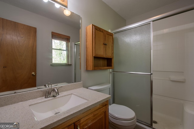 bathroom featuring toilet, a shower with door, and vanity