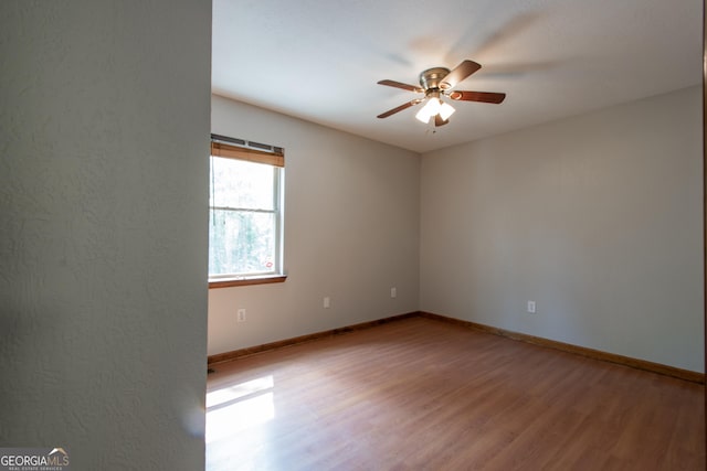 spare room featuring baseboards, a ceiling fan, and wood finished floors