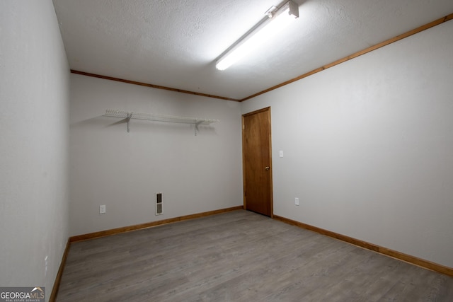 spare room featuring baseboards, ornamental molding, wood finished floors, and visible vents