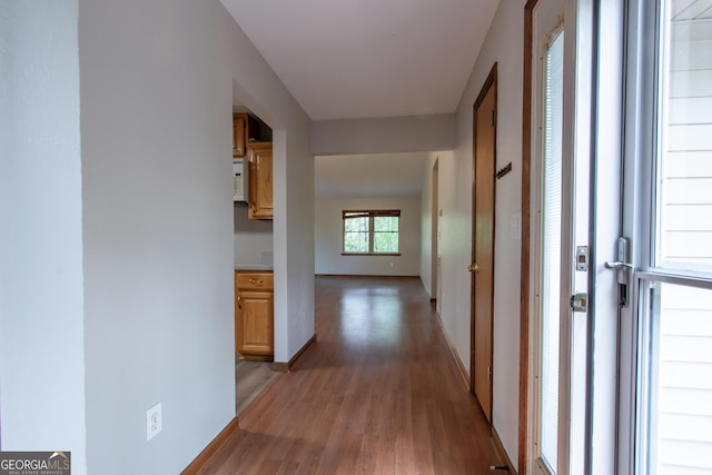 corridor featuring baseboards and light wood-type flooring