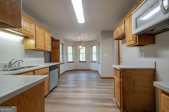 kitchen with a sink, light wood-style floors, light countertops, white microwave, and stainless steel dishwasher