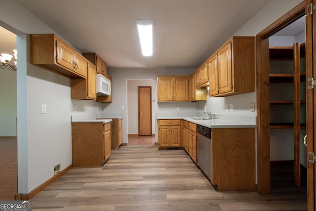 kitchen with stainless steel dishwasher, a sink, baseboards, white microwave, and light wood-style flooring