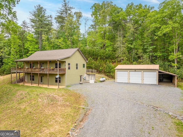 garage with a forest view, gravel driveway, and a garage
