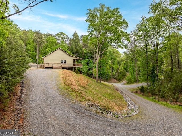view of front of home featuring a forest view, driveway, and a wooden deck