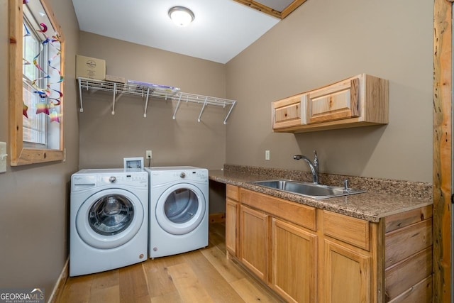 laundry area with baseboards, washer and clothes dryer, cabinet space, a sink, and light wood finished floors