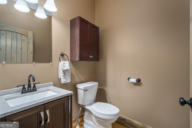 bathroom with toilet, baseboards, wood finished floors, and vanity