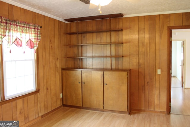 interior space featuring wood walls, light wood finished floors, and ornamental molding
