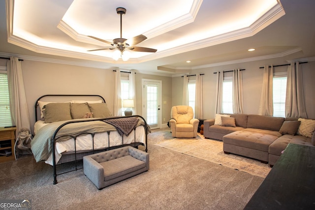 bedroom with ornamental molding, a tray ceiling, carpet flooring, and multiple windows
