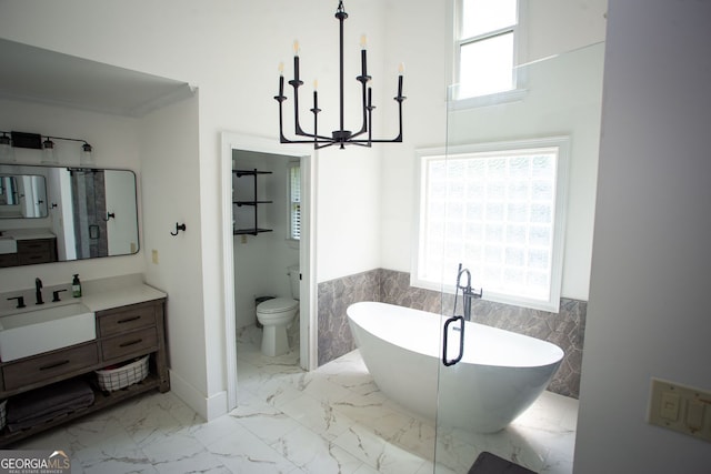 bathroom with an inviting chandelier, wainscoting, marble finish floor, tile walls, and a soaking tub
