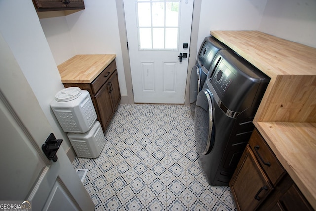 clothes washing area featuring cabinet space and washer and clothes dryer
