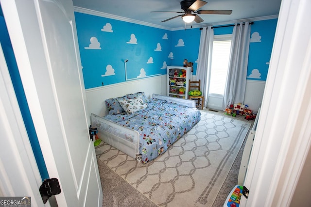 carpeted bedroom with a ceiling fan, wainscoting, and ornamental molding