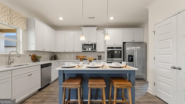 kitchen featuring a breakfast bar area, crown molding, appliances with stainless steel finishes, a sink, and white cabinets