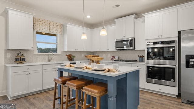 kitchen with light countertops, appliances with stainless steel finishes, visible vents, and a center island