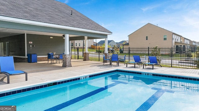 community pool with fence and a patio area