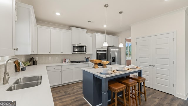 kitchen with crown molding, a sink, stainless steel appliances, white cabinetry, and tasteful backsplash