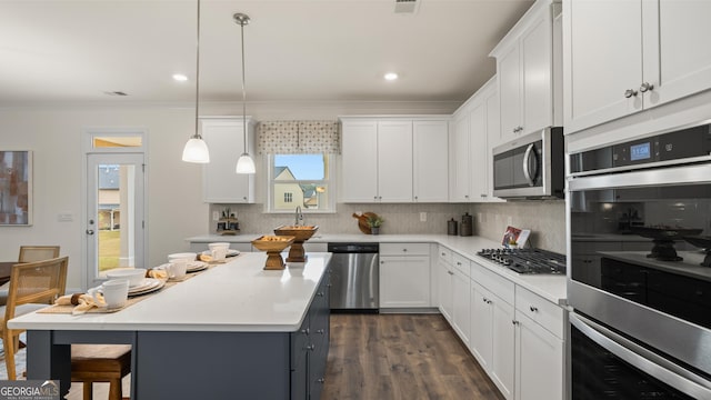 kitchen featuring light countertops, stainless steel appliances, white cabinetry, backsplash, and ornamental molding