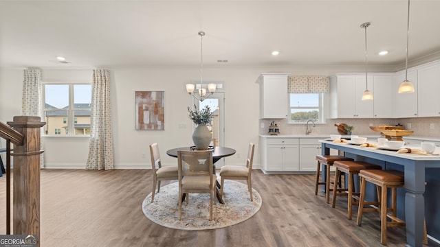 dining area with crown molding, an inviting chandelier, recessed lighting, and wood finished floors