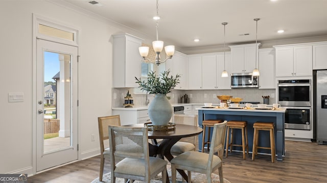 kitchen featuring ornamental molding, stainless steel appliances, tasteful backsplash, and white cabinetry