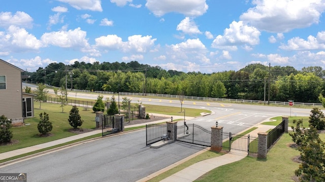 view of property's community featuring fence, a gate, and a lawn