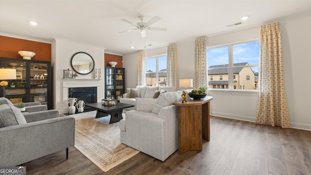 living area featuring visible vents, a ceiling fan, wood finished floors, and ornamental molding