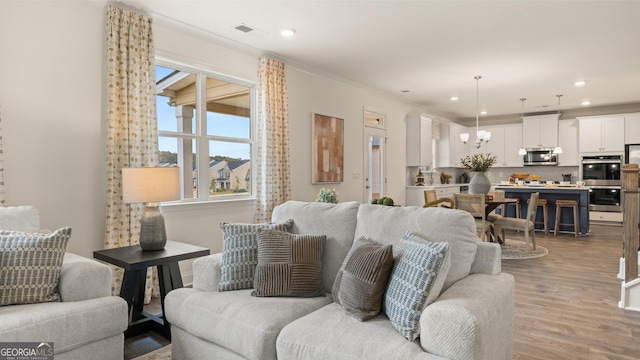 living area with recessed lighting, an inviting chandelier, light wood-type flooring, and visible vents