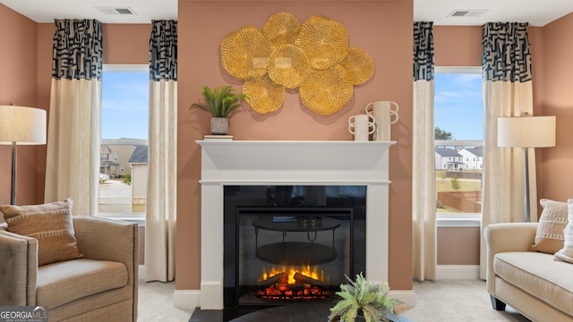 living area featuring a glass covered fireplace, baseboards, carpet flooring, and visible vents