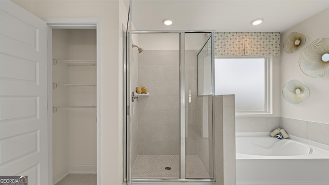 full bathroom featuring recessed lighting, a walk in closet, a bath, and a stall shower