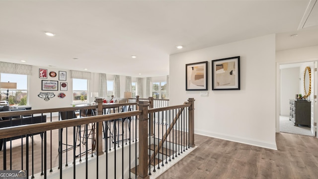 hall with a healthy amount of sunlight, attic access, wood finished floors, and an upstairs landing