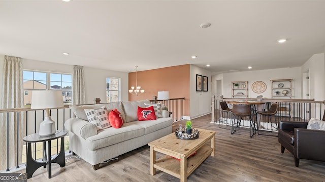 living area featuring recessed lighting, baseboards, a notable chandelier, and wood finished floors