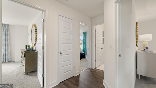 corridor featuring baseboards, carpet floors, and wood finished floors