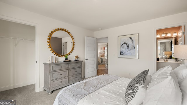 bedroom with light colored carpet, connected bathroom, baseboards, and a closet