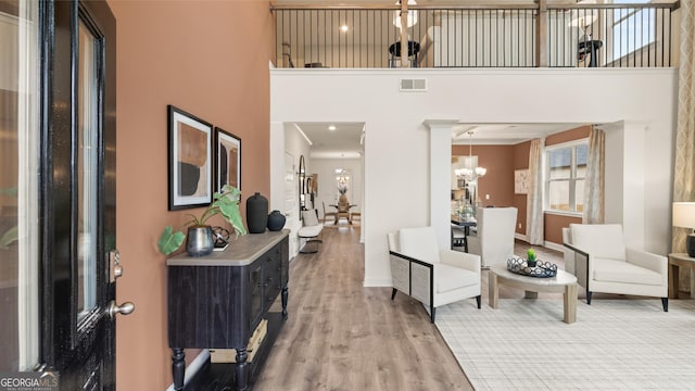 living room with visible vents, wood finished floors, baseboards, a high ceiling, and a chandelier