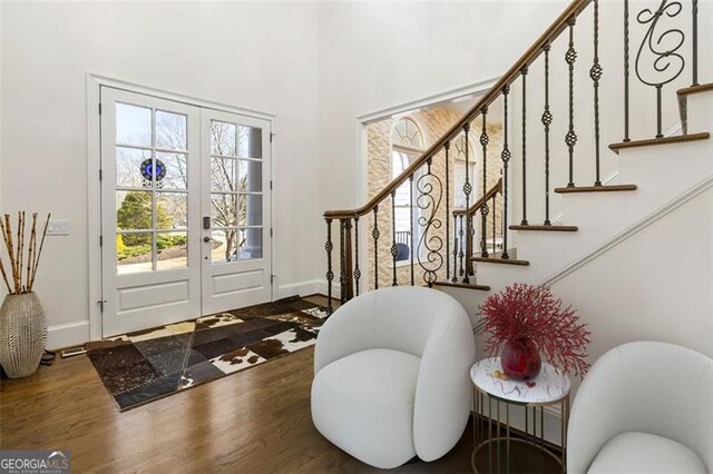entryway with a high ceiling, french doors, stairs, baseboards, and wood finished floors