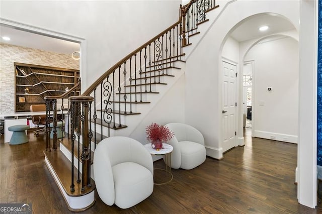stairway featuring arched walkways, baseboards, and wood finished floors