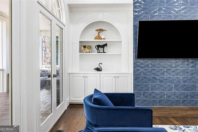 sitting room with french doors, dark wood finished floors, and built in shelves
