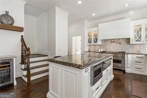 kitchen featuring dark wood-type flooring, ornamental molding, tasteful backsplash, and dark stone countertops
