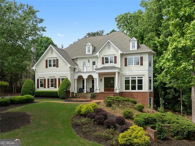 view of front facade with french doors, a balcony, covered porch, and a front yard