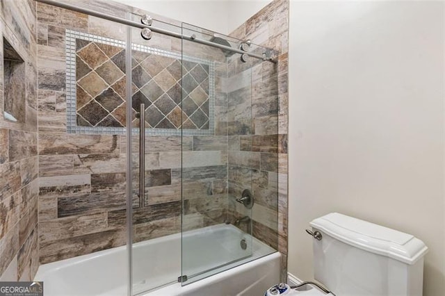 bathroom with bath / shower combo with glass door and toilet