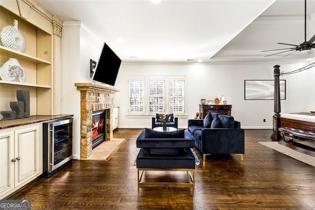 living room featuring a stone fireplace, wine cooler, and wood finished floors