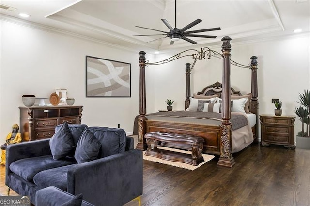 bedroom with a tray ceiling, wood finished floors, and visible vents