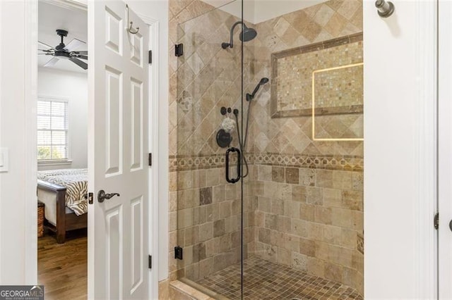 ensuite bathroom featuring ceiling fan, a shower stall, wood finished floors, and connected bathroom