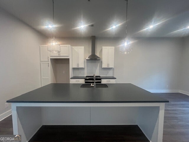 128 Bert Ln SE Unit 167, Atlanta, GA 30316 - kitchen featuring wall chimney range hood, dark countertops, white cabinetry, dark wood finished floors, and an island with sink
