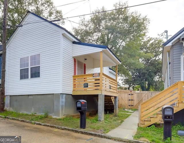 view of home's exterior featuring stairs, a wooden deck, and fence