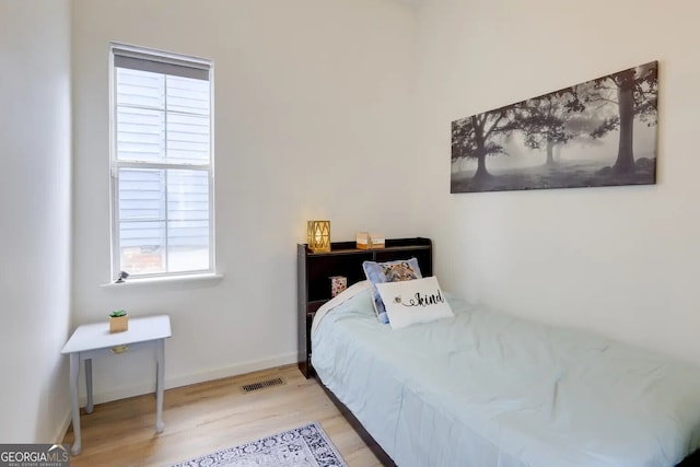 bedroom featuring light wood finished floors and baseboards