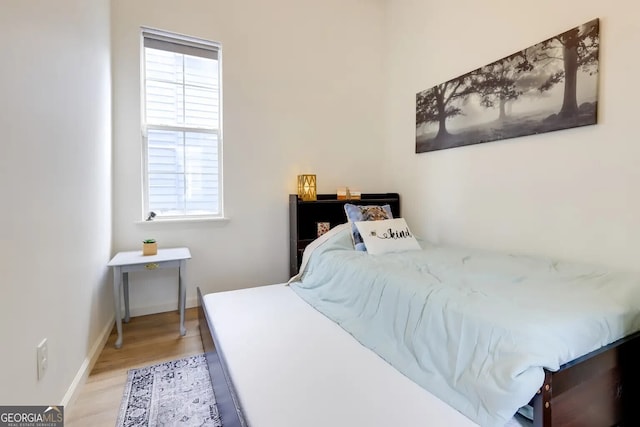 bedroom with light wood finished floors and baseboards