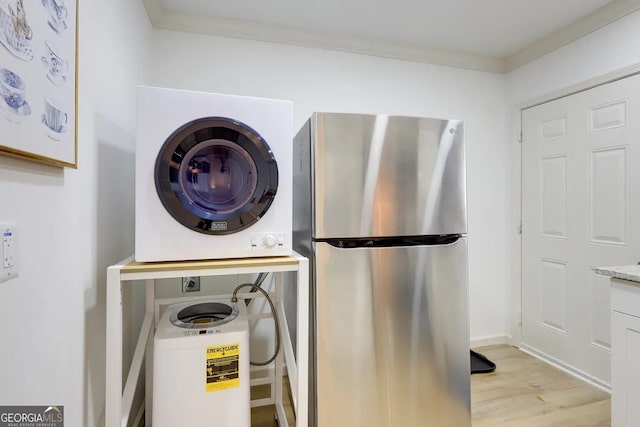 laundry room featuring stacked washer / dryer and light wood-type flooring