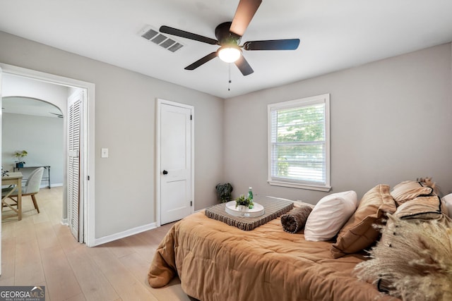 bedroom with baseboards, ceiling fan, light wood finished floors, and visible vents